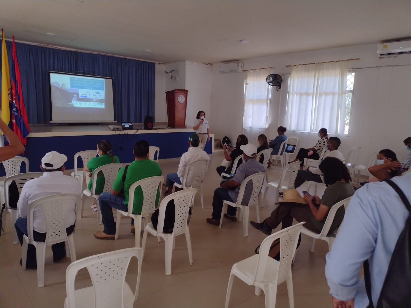 Grupo de personas reunidas en el taller sentados en una silla con expositor al frente
